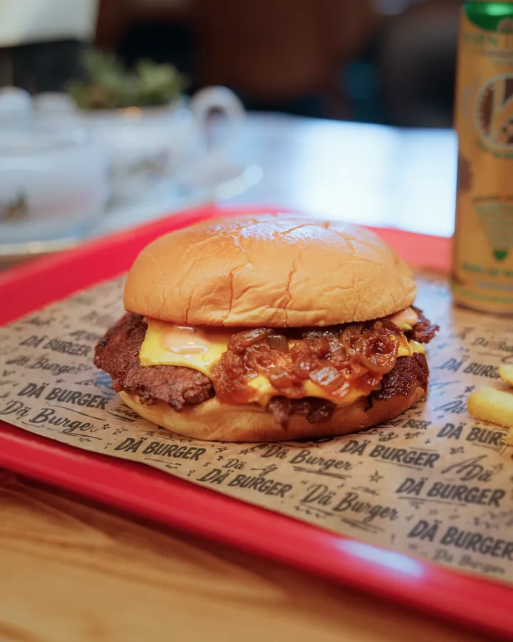 Ein Smashburger mit Pommes auf dem roten Tablett mit DÄ-Burgerpapier